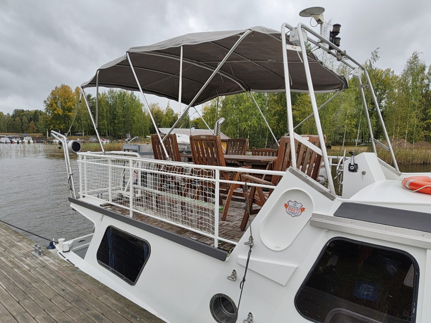 Überdachtes Oberdeck des Bootes mit Sitzgruppe am finnischen Seeufer