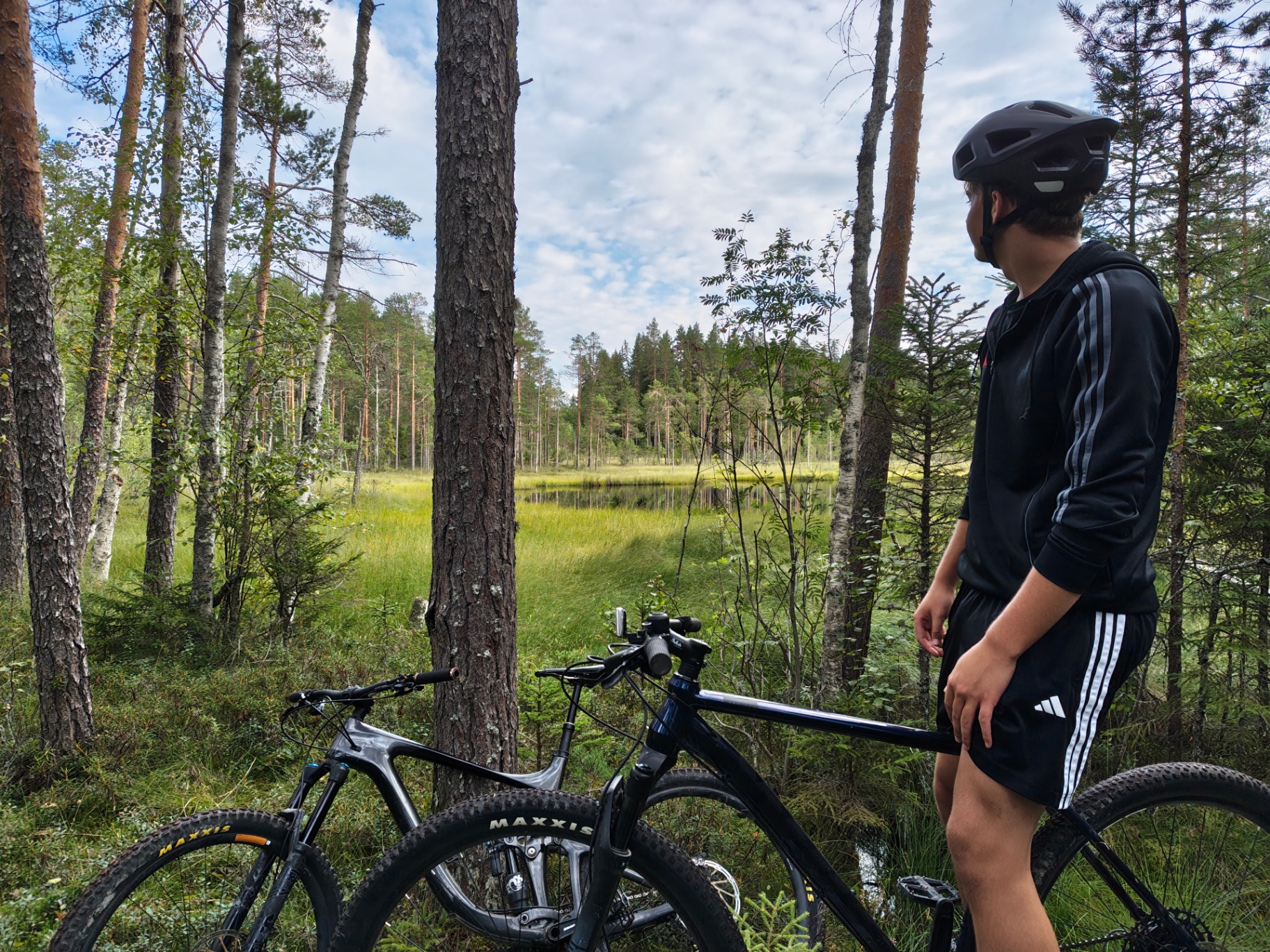 Ciclista con bicicletas junto a un lago y bosque de Finlandia en verano