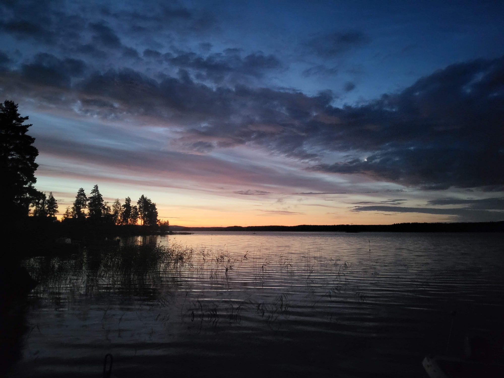 Finnish lake at dusk with dramatic clouds reflected in still water