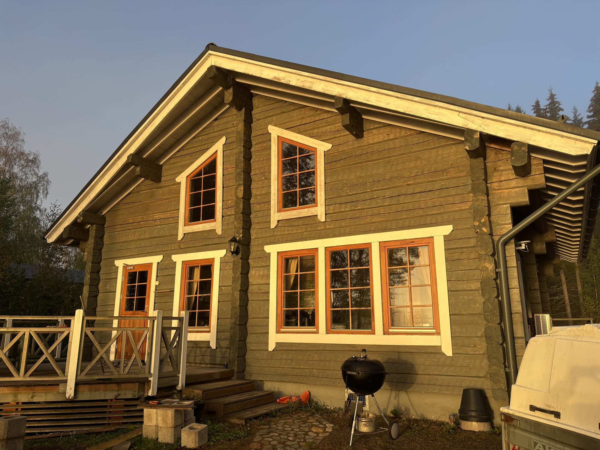 Traditional Finnish log cottage with a terrace, photographed in the evening sun