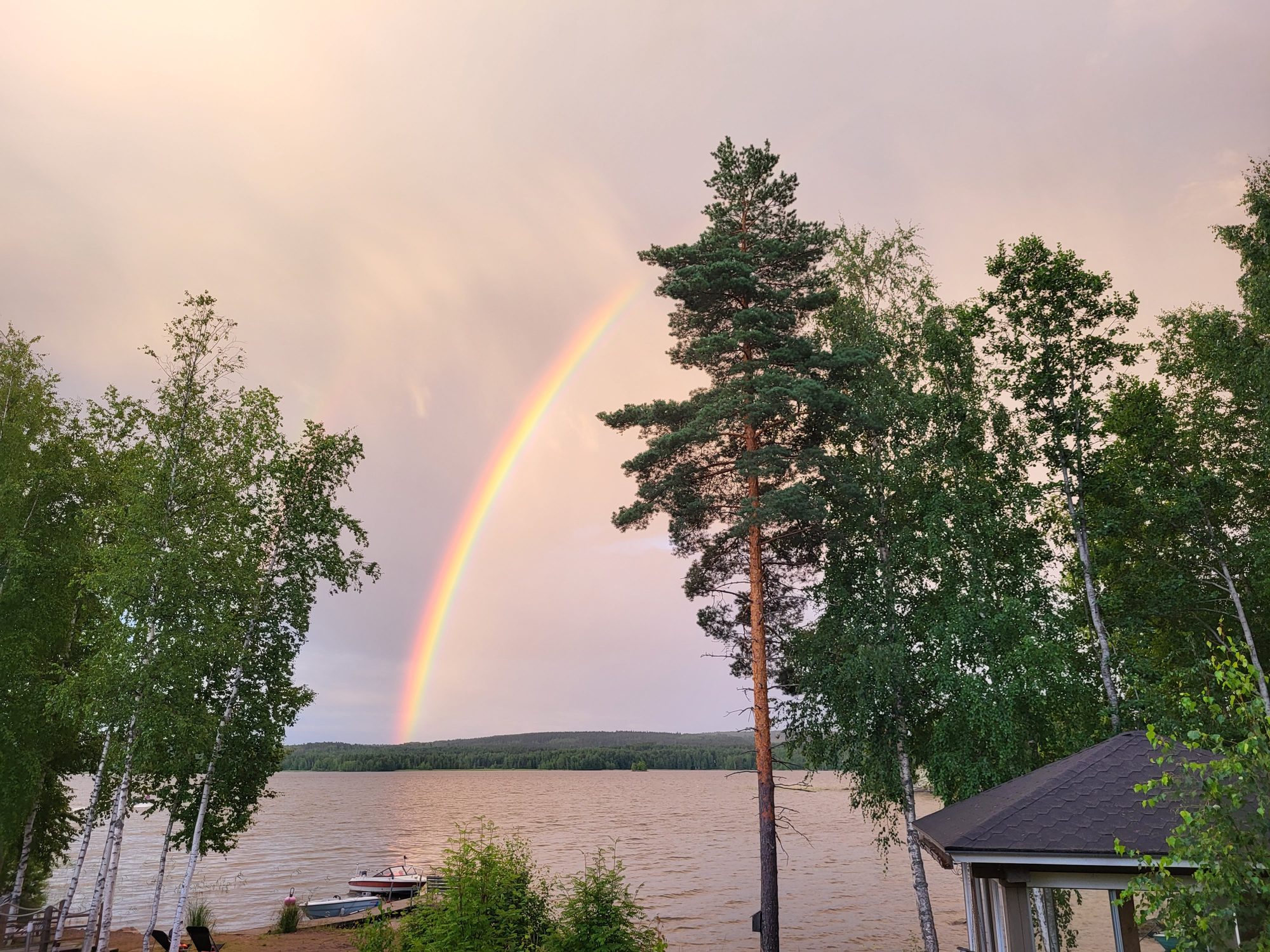 Rainbow over a Finnish lake seen from the cottage shore