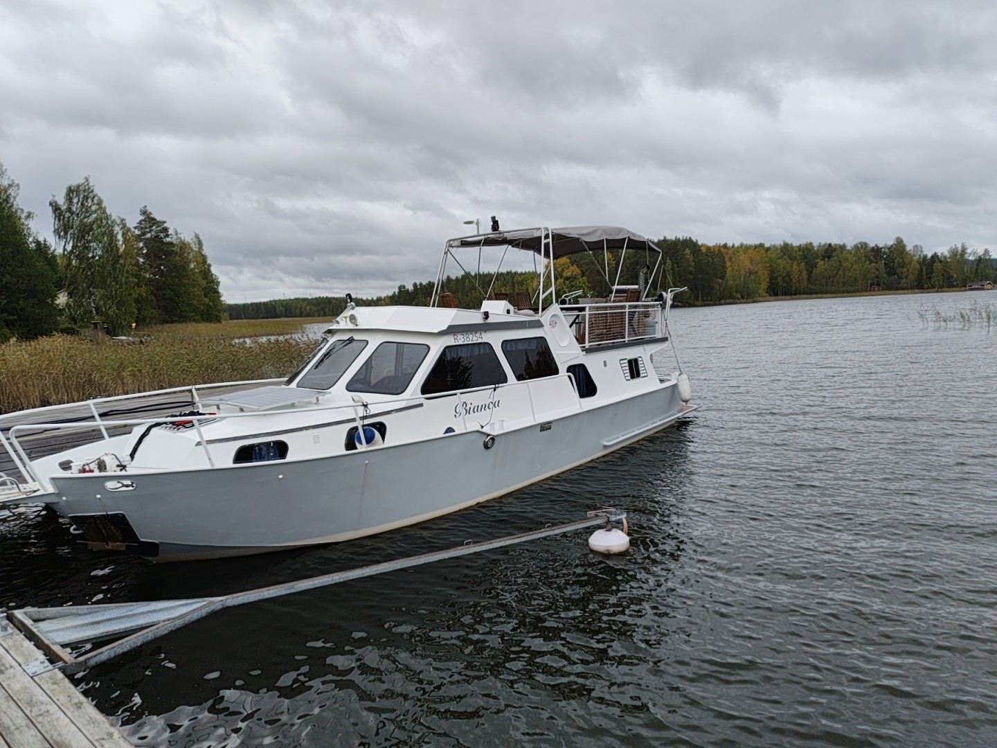 Private motor boat moored at a wooden jetty on a calm Finnish lake surrounded by forest