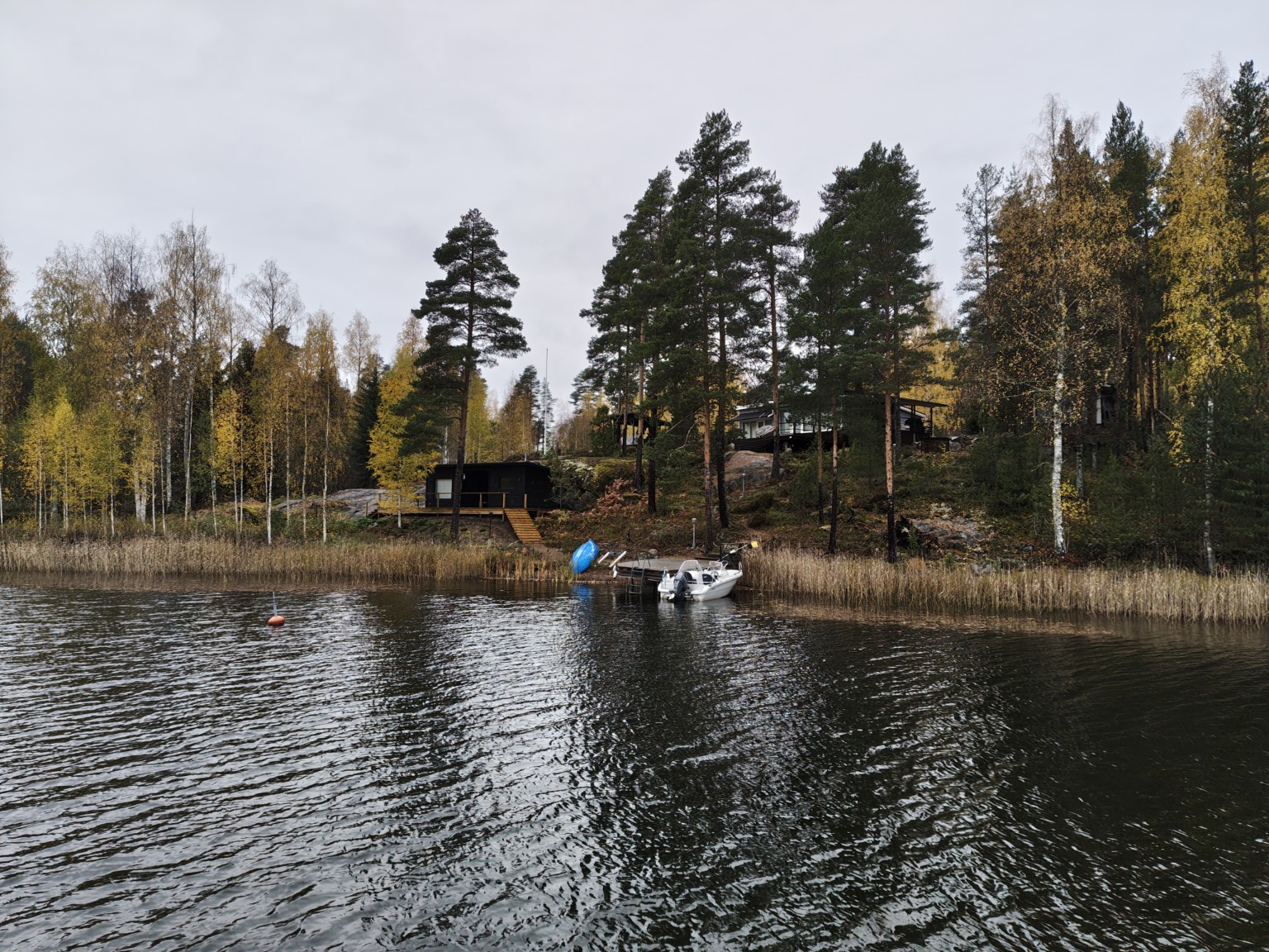 Lakeside buildings and a small boat among autumn trees in Finland in October