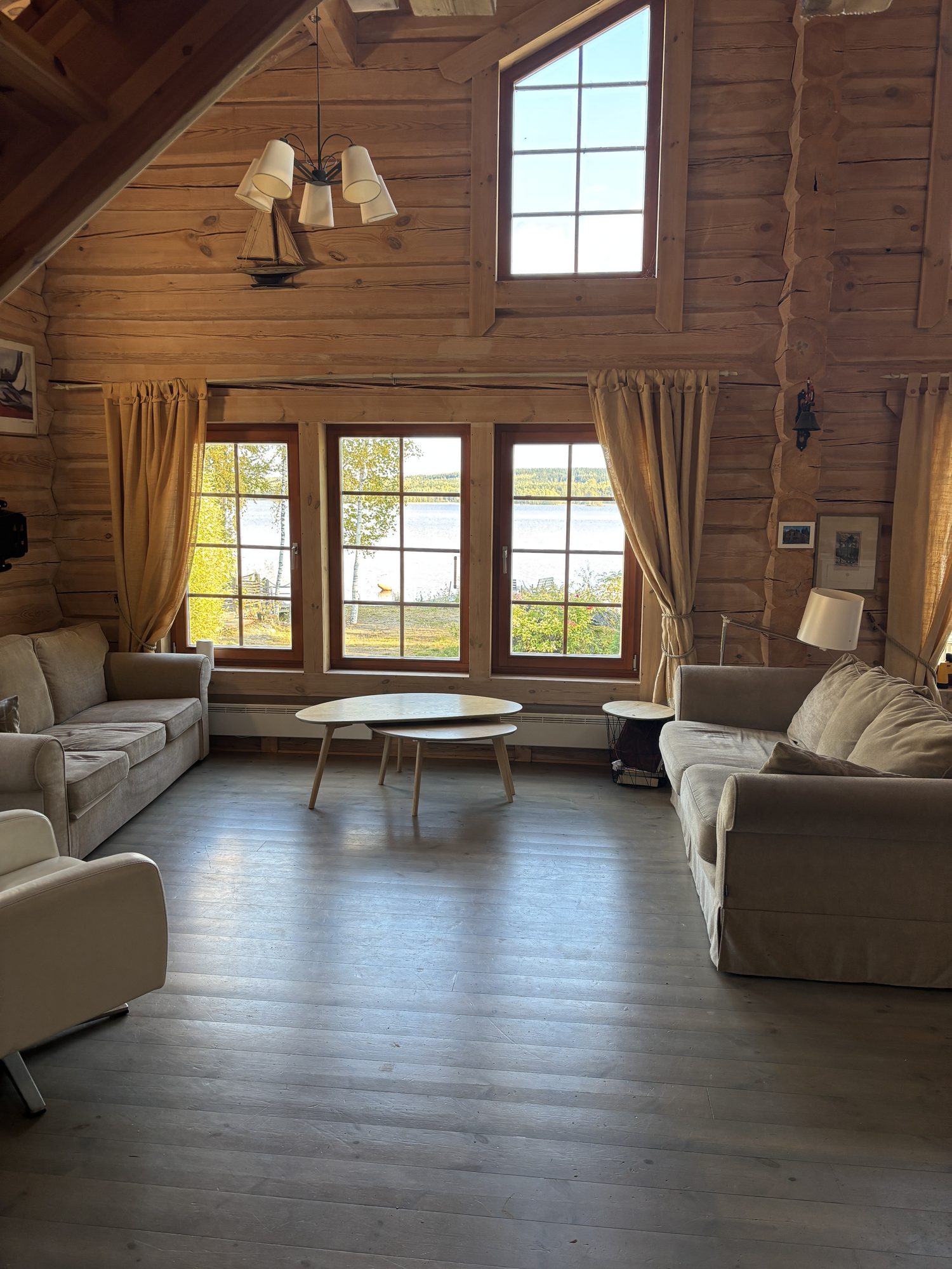 Cottage living room with sofas and large windows facing the lake