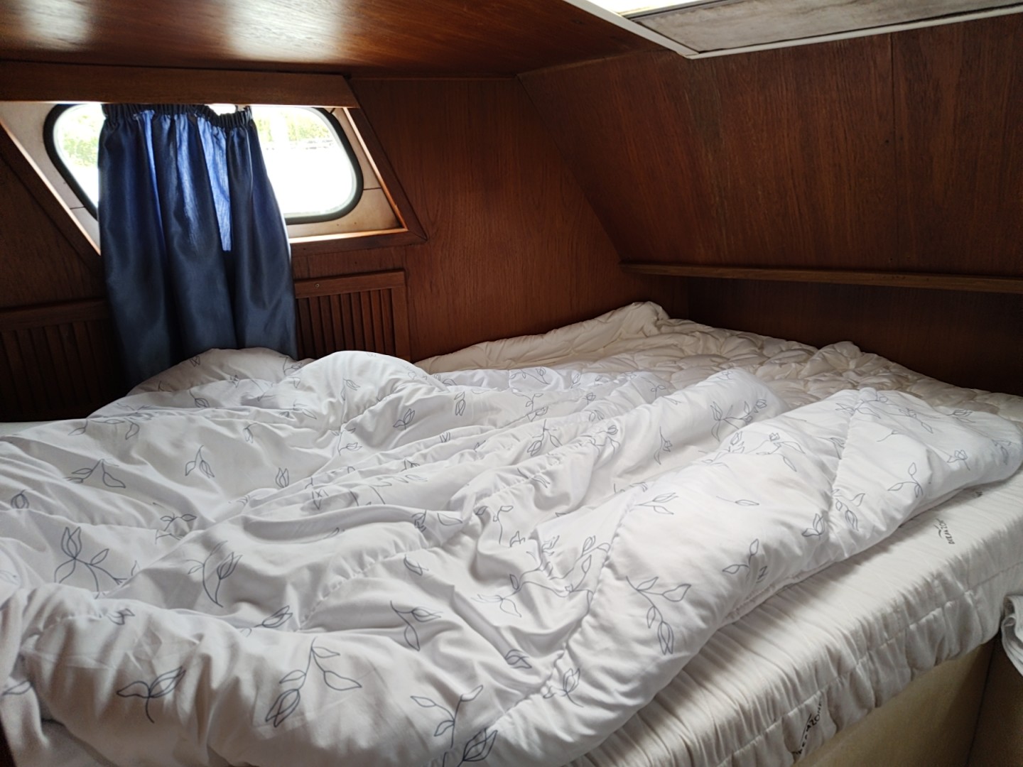 Gemütliches Doppelbett in der holzverkleideten Schlafkabine des Bootes