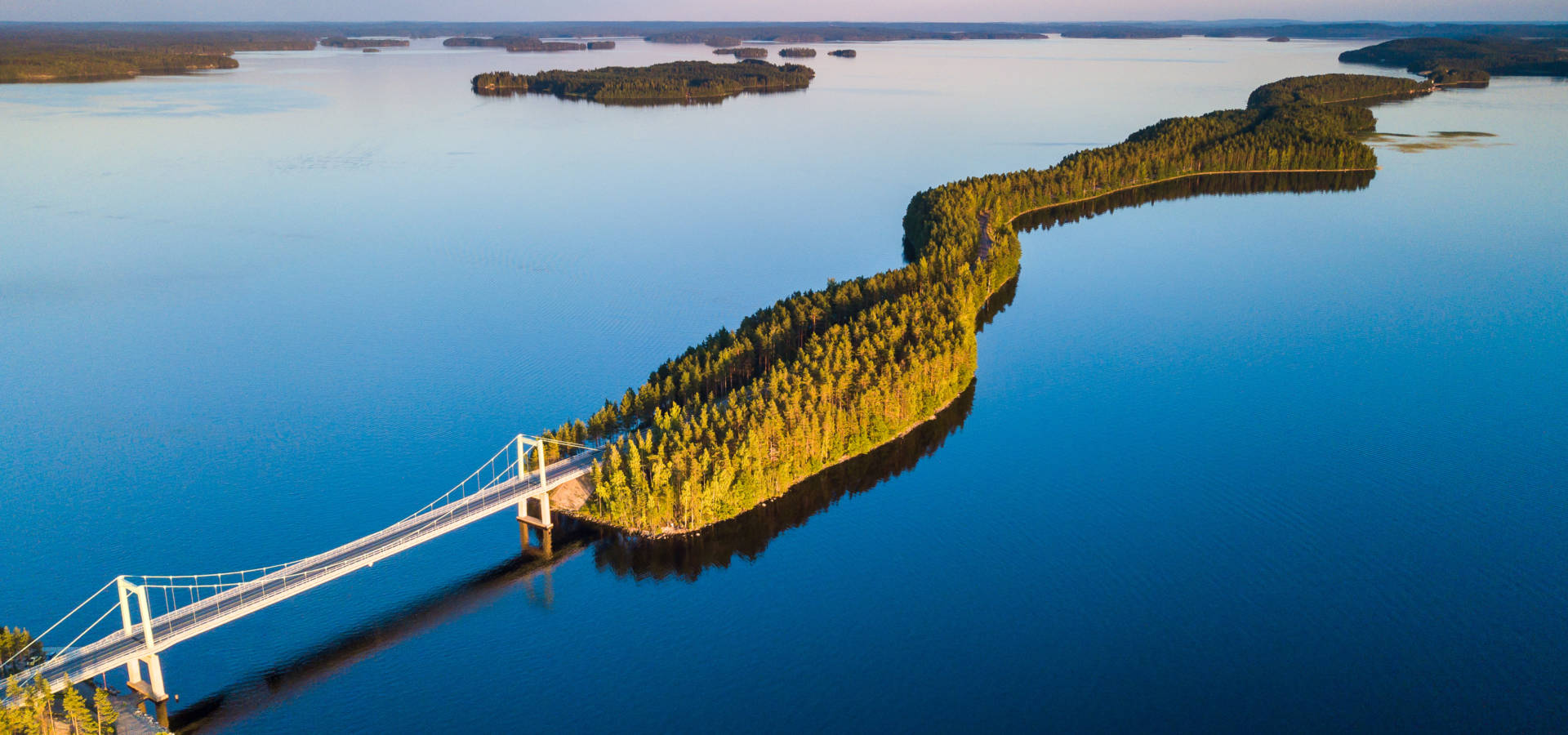 Aerial view of the Pulkkilanharju bridge and forested ridge surrounded by Lake Päijänne in Finnish Lakeland