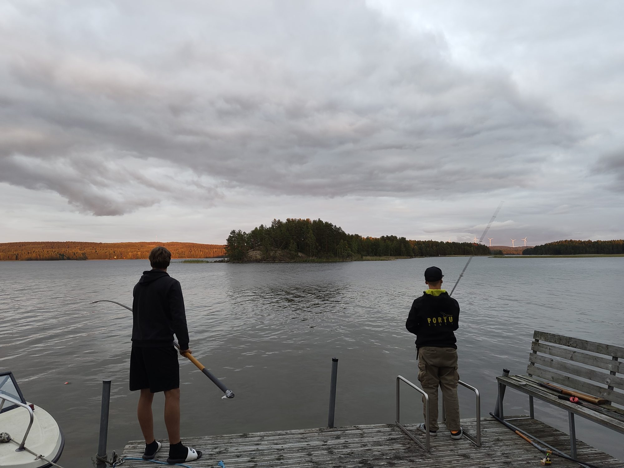Two people fishing from the cottage jetty in the evening light