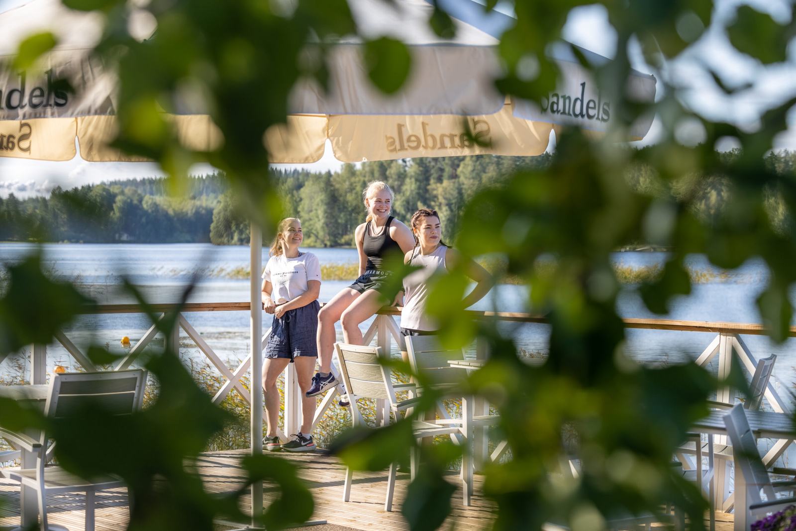 Guests walking along a lakeside path surrounded by summer greenery