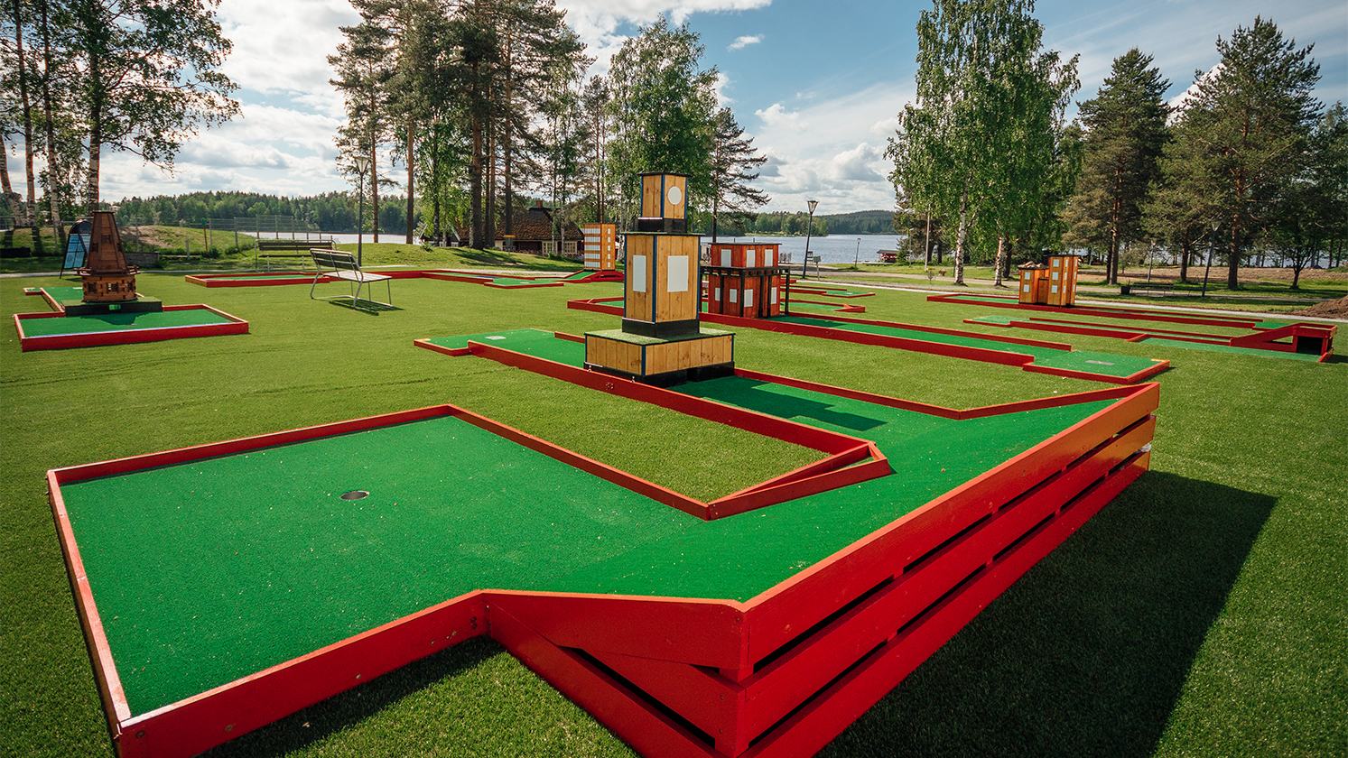Minigolf course on green lawn beside the lake in summer