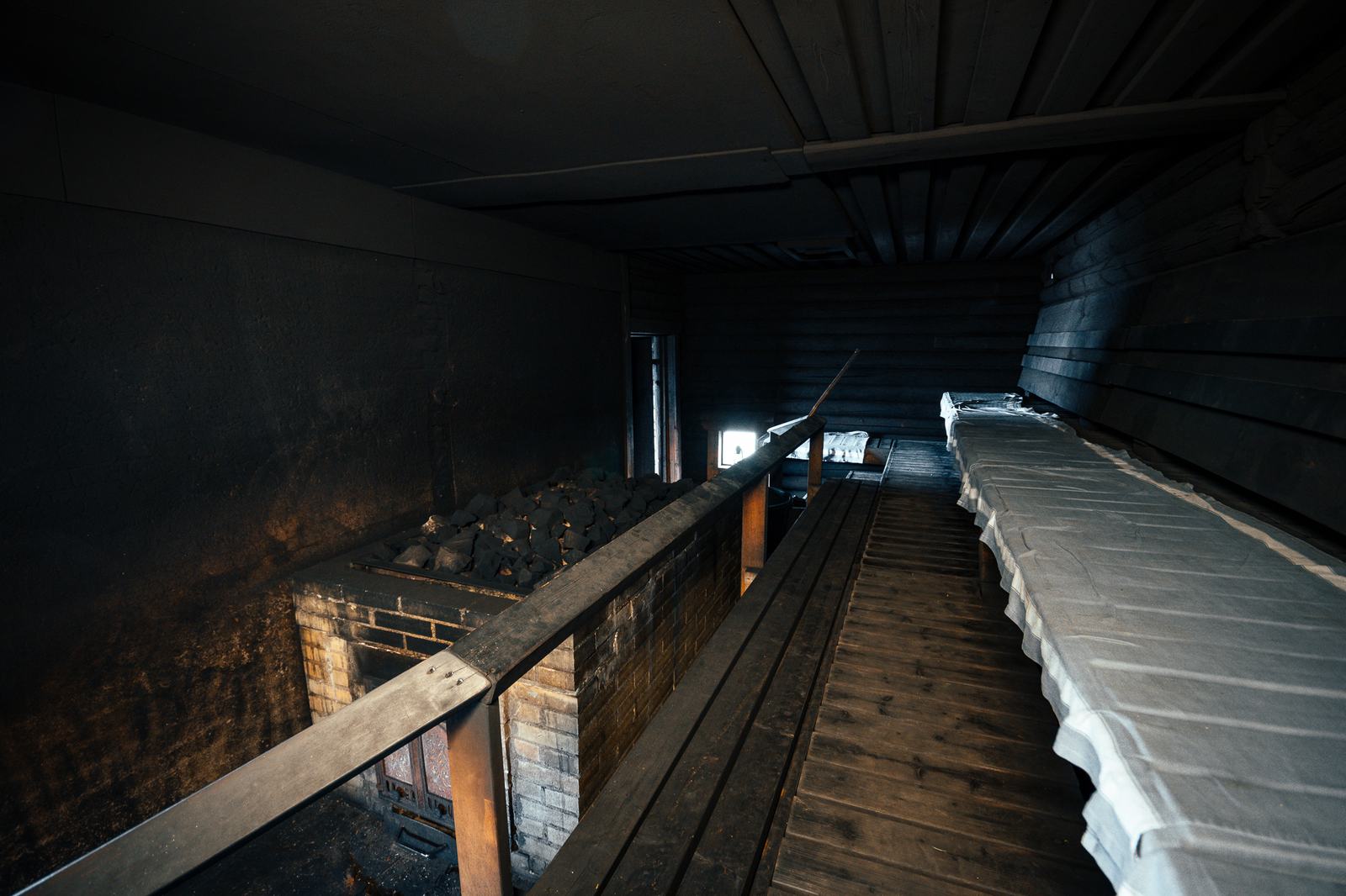 Dark timber interior of a traditional Finnish smoke sauna with wooden benches