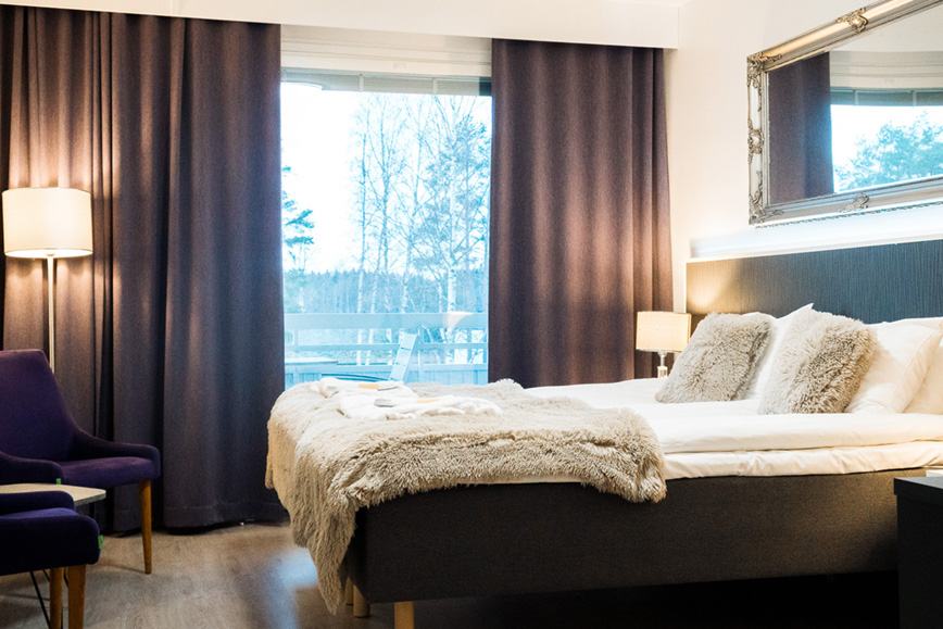 A simple, light room with a wide window looking out over the lake and forest